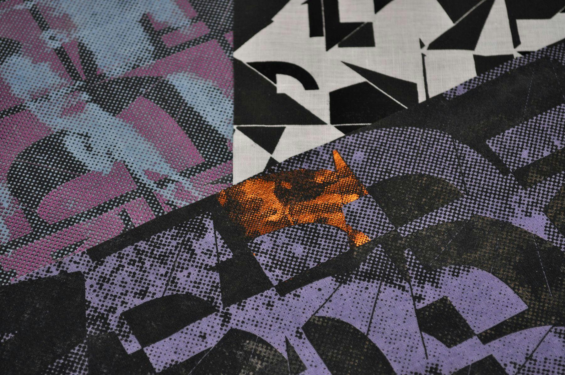 A photograph of a printed design with abstract shapes. One third of the design has a dark pink background with blue and black shapes. The other third has a white background with black shapes and the last part of the design has purple shapes on a black background.