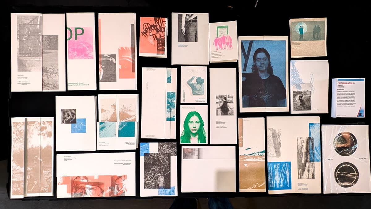 A collection of artistic printed materials arranged on a black background, featuring various images, text, and graphic designs.