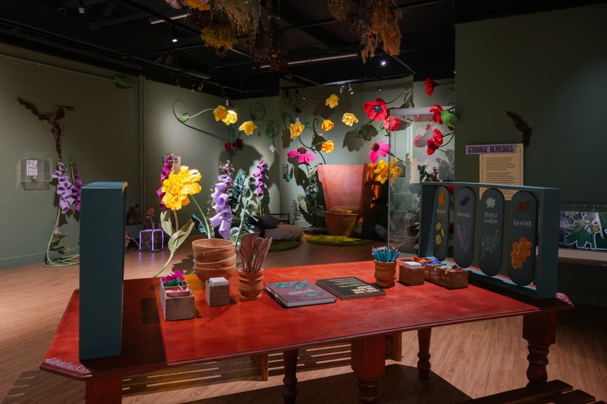 Colourful, oversized flowers and educational displays in a museum. A wooden table with crafts and books is in the foreground.
