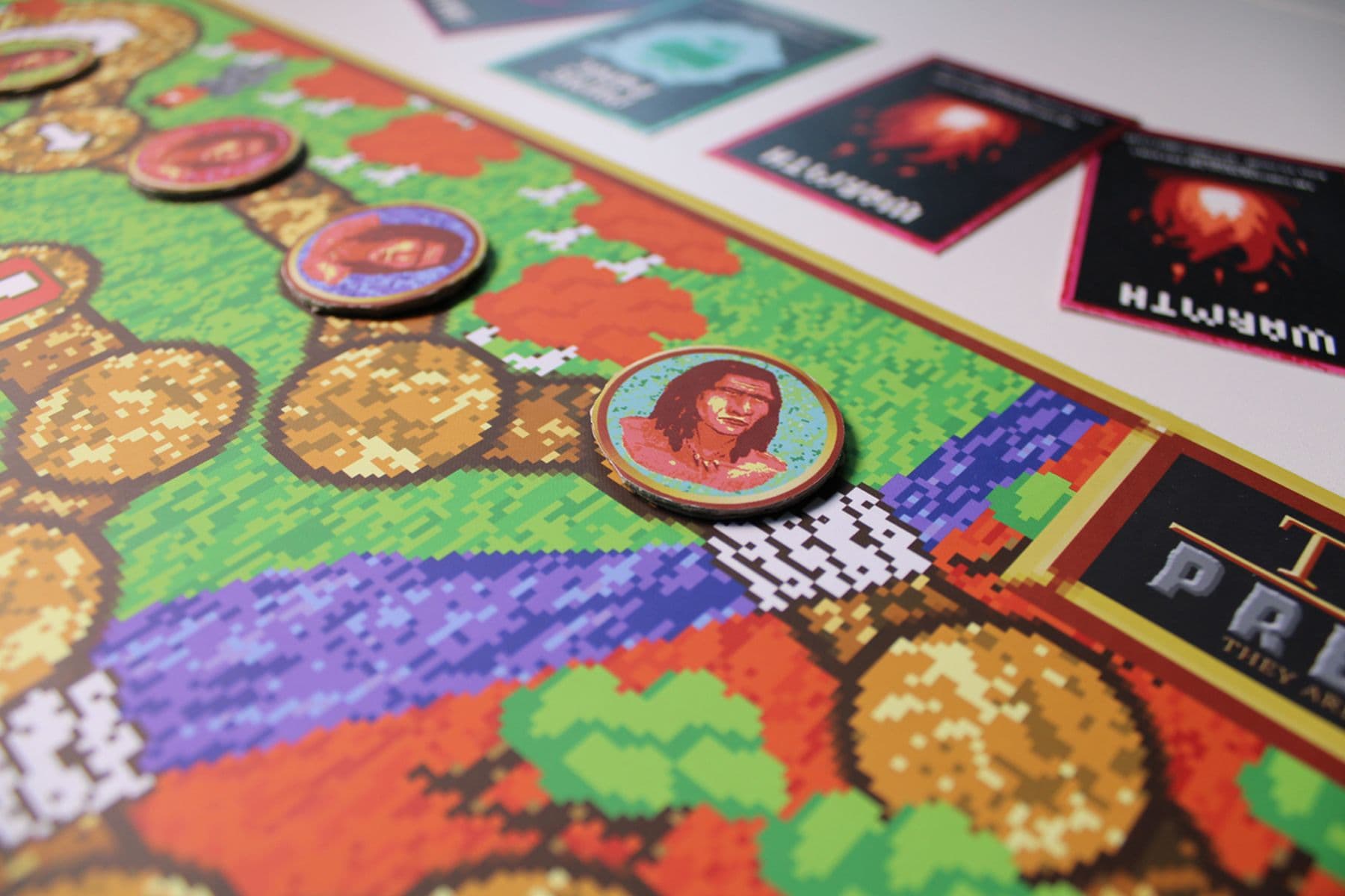 An image of a colourful board game with pixilated graphics, circular character tokens and cards with white text.