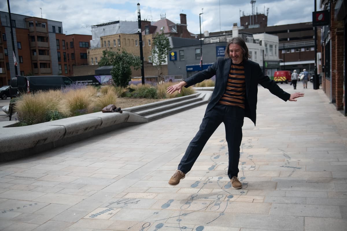 A person stands on a paved street with outlined dance steps inscribed.