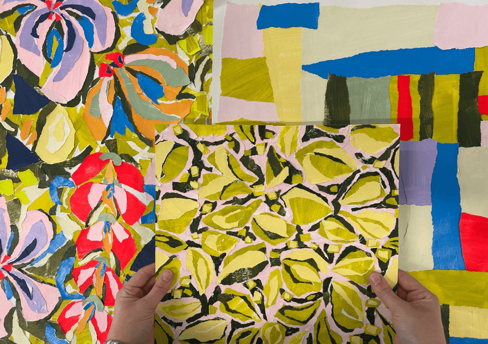 Hands holding a vibrant abstract painting with green, yellow, and black patterns, placed over two colourful abstract artworks.