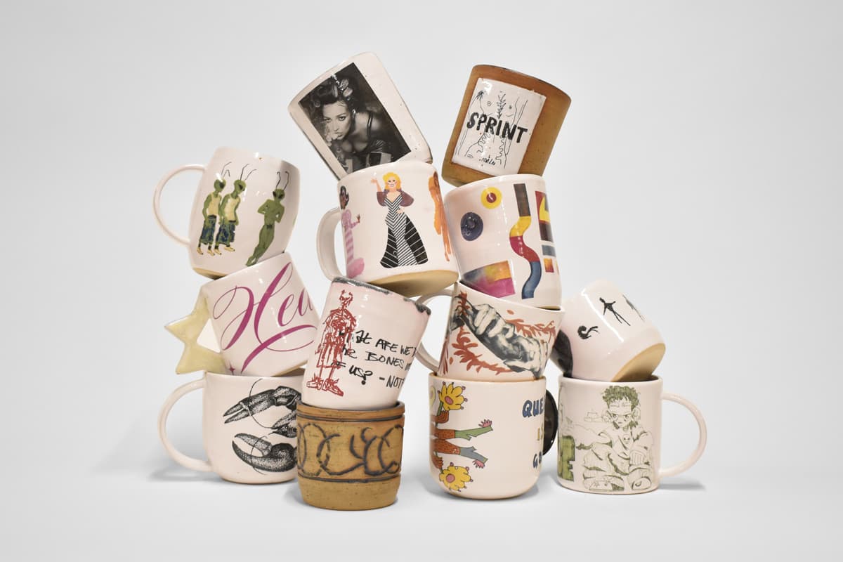 Collection of ceramic mugs with various designs and illustrations against a white background.