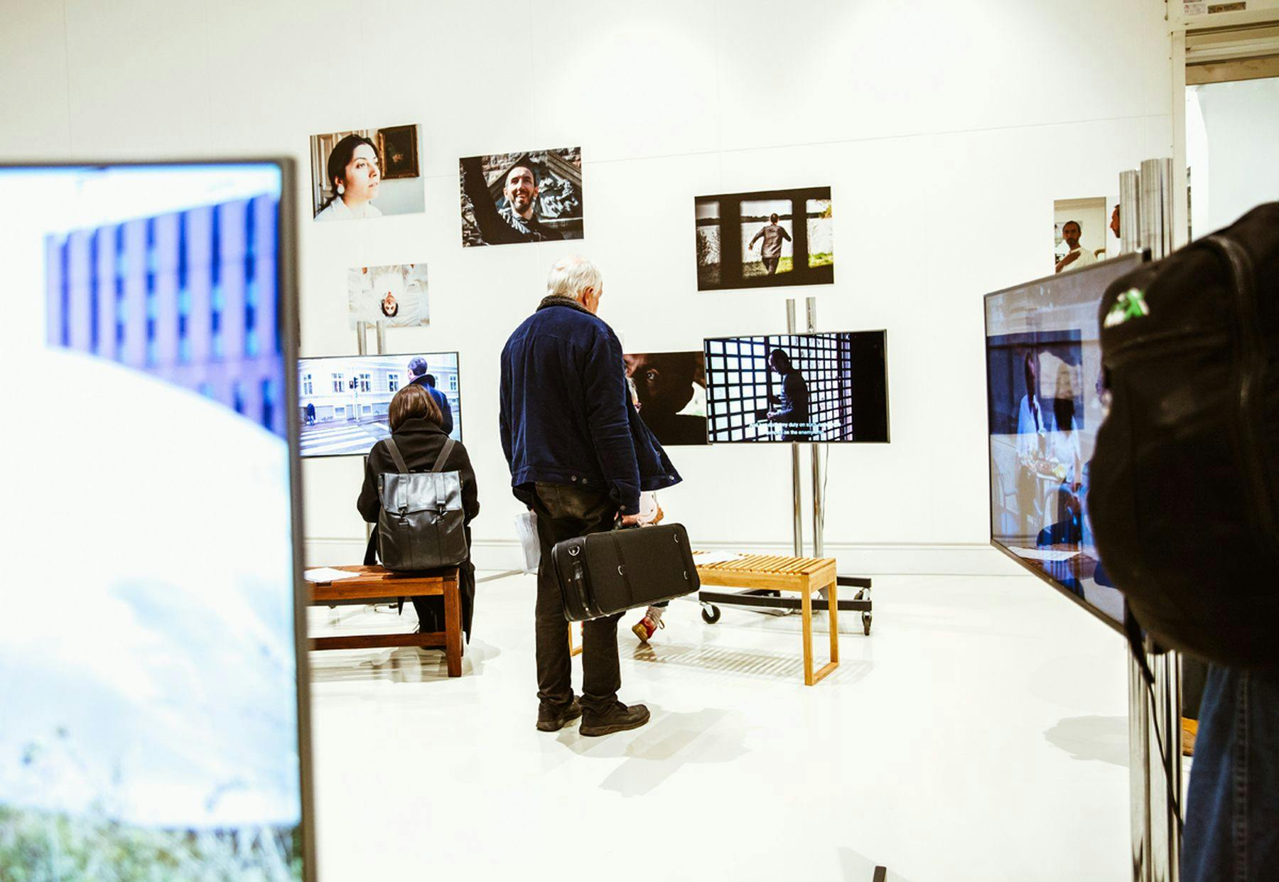 A photograph of people viewing photographs and screens at a gallery.