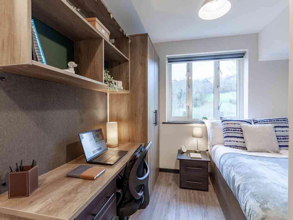 A photograph of The Leather Works room ensuite room, featuring a desk  a bed and a bedside cabinet.