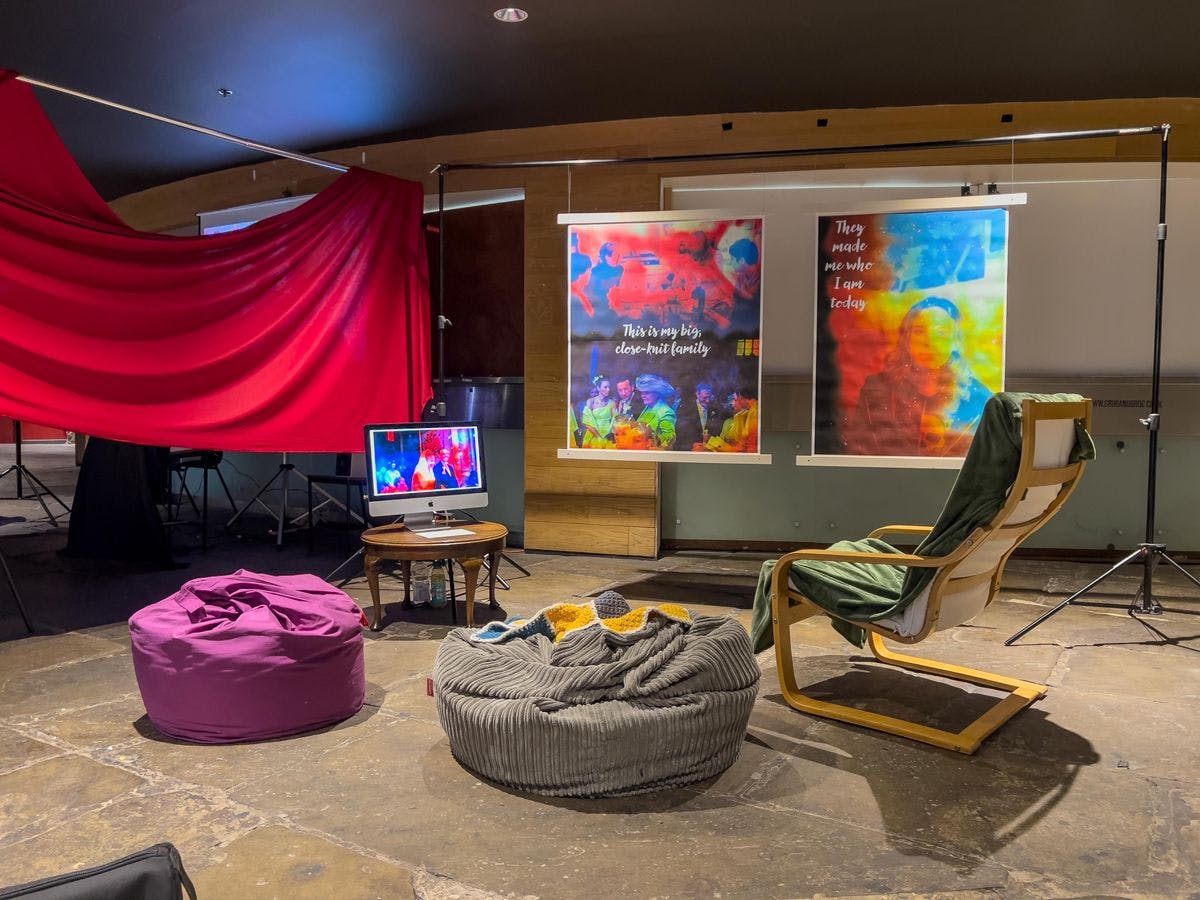 Chair and two beanbags in front of two brightly coloured banners and a red sheet. A screen shows the same bright images.