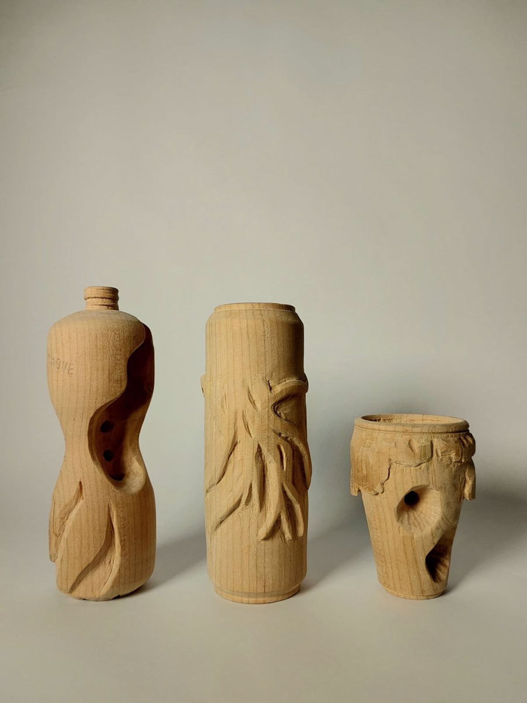 Three carved wooden bottles with intricate designs and textures, displayed against a plain background.